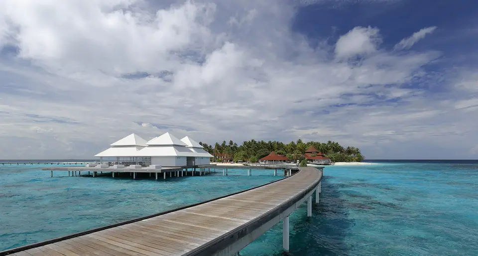 Wooden walkway leading to overwater villas above a clear Maldives lagoon