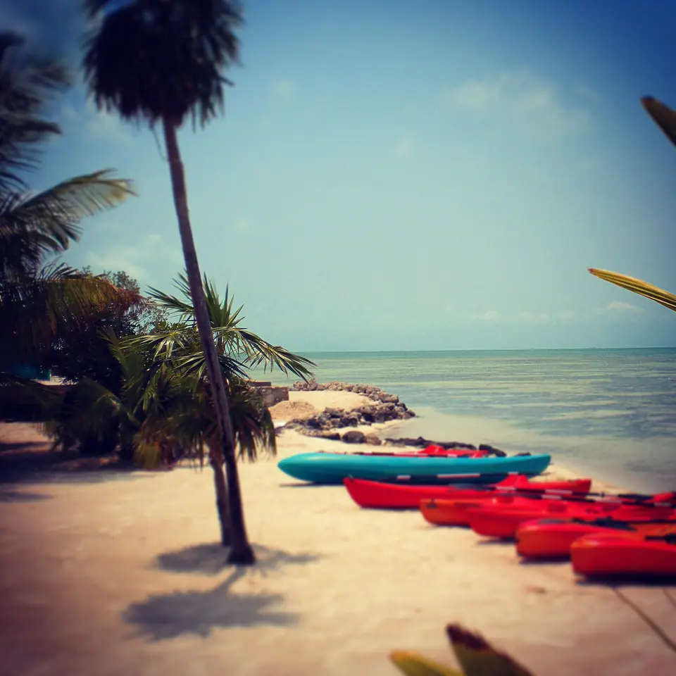 Two sea kayaks pulled up on the sand beside clear shallow water at Cayo Espanto