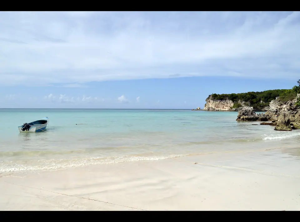 Wide sandy Playa Macao with waves rolling in and green hills behind the beach