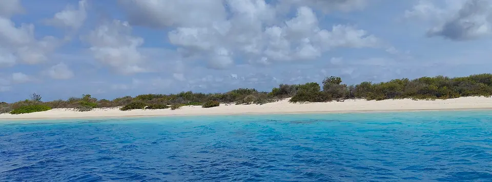 Low, scrub-covered Klein Bonaire with a thin white beach seen across deep blue water