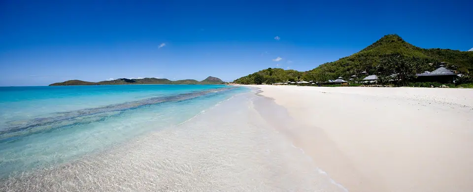 Panoramic view of a curved sandy beach and calm bay at Hermitage Bay, Antigua