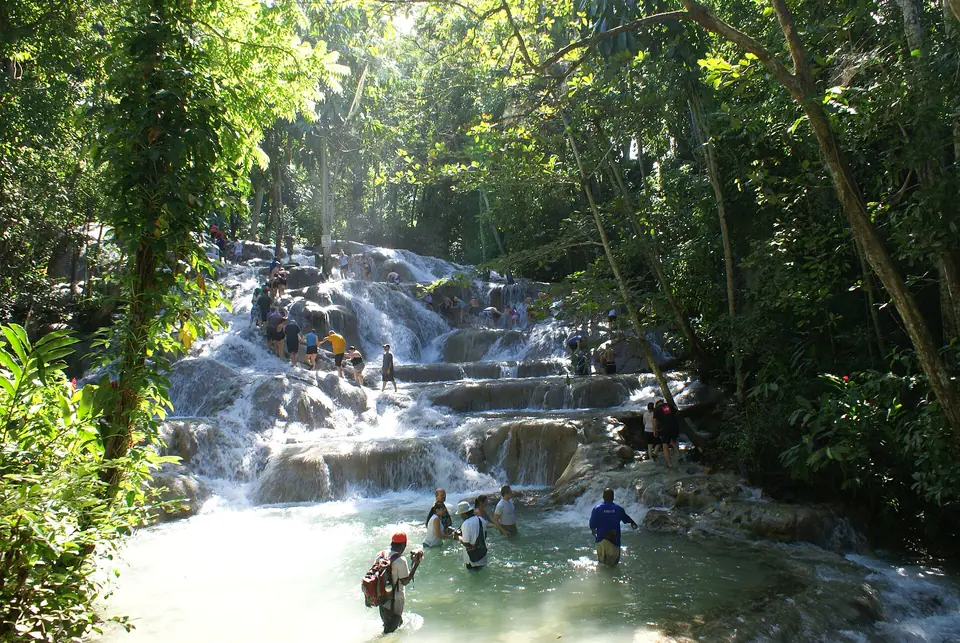 Tourists holding hands as they climb the limestone terraces of Dunn's River Falls with a guide