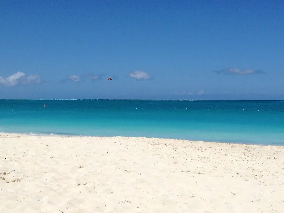 Wide white-sand beach meeting bright turquoise water under a blue sky at Grace Bay, Turks and Caicos