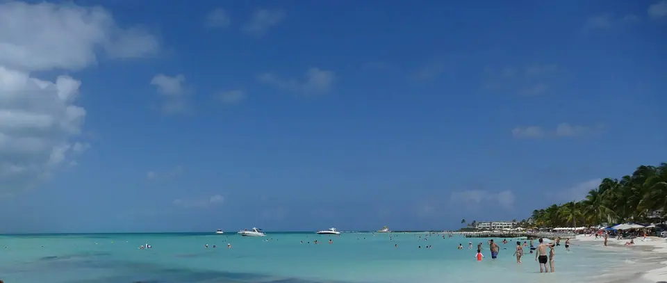 Shallow, pale turquoise water and white sand at Playa Norte on Isla Mujeres, with swimmers wading far from shore