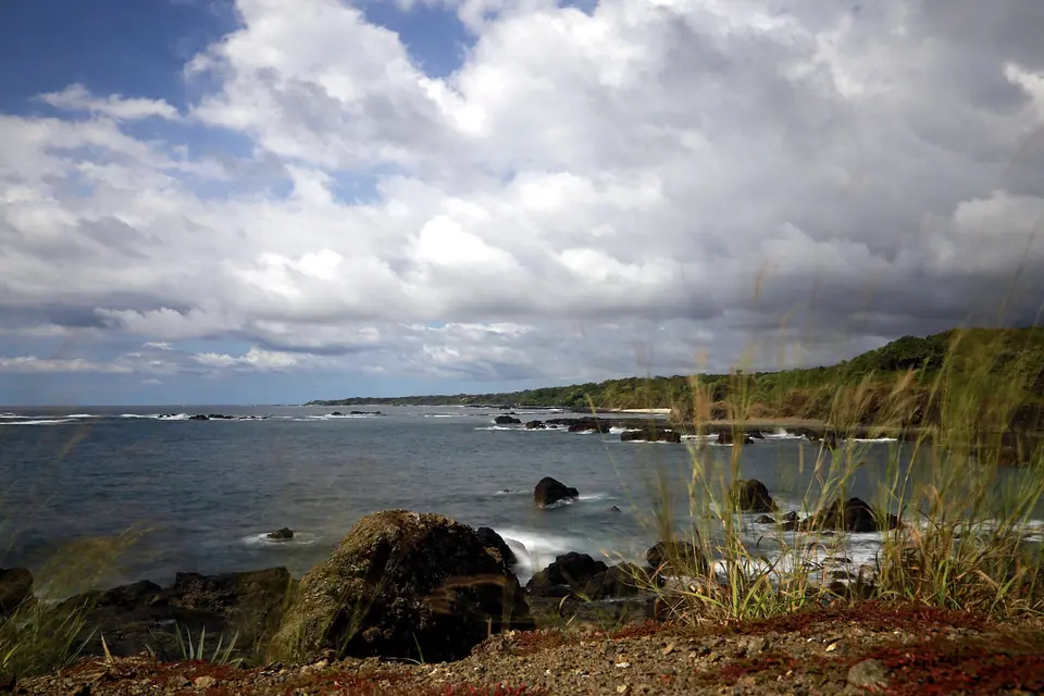 Rocky shoreline and waves under cloudy skies at Playa Juanillo, Cap Cana