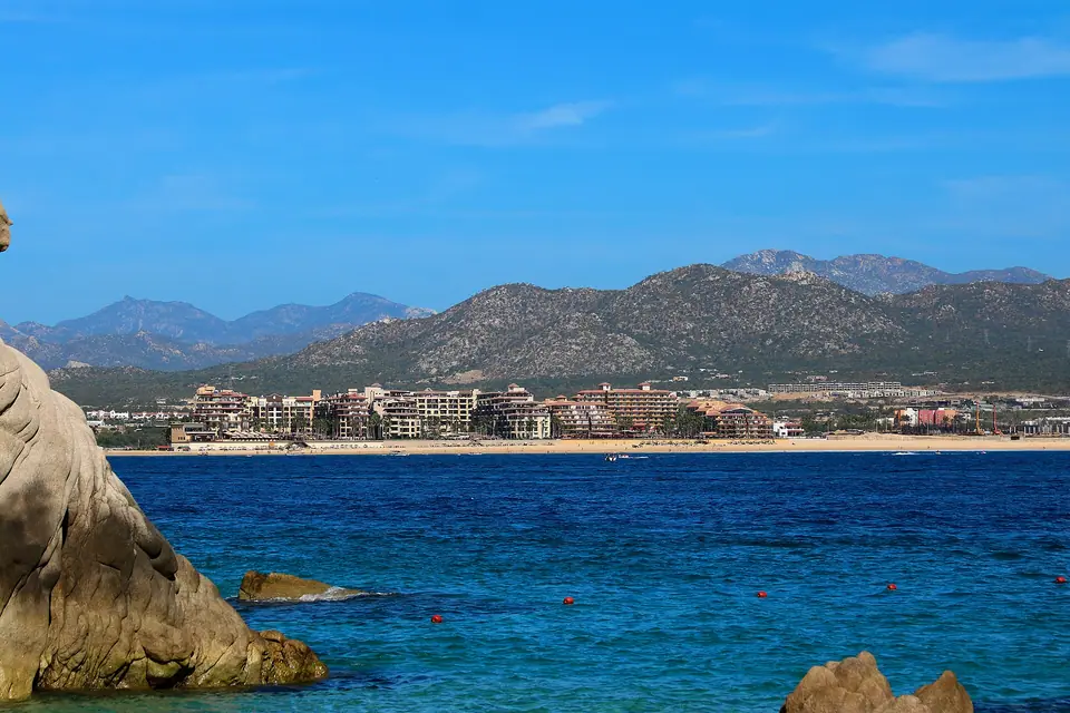 Panorama of Medano Beach in Cabo San Lucas with swimmers, umbrellas and anchored boats