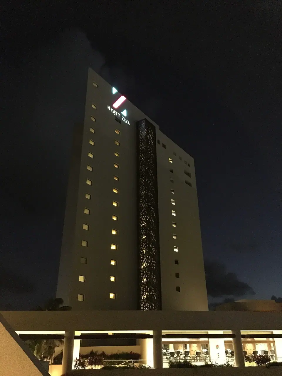 Hyatt Ziva Cancun's lit-up hotel tower against a dark night sky