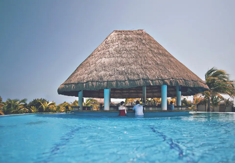 Pool and palm trees in front of Moon Palace Golf & Spa Resort buildings in Mexico