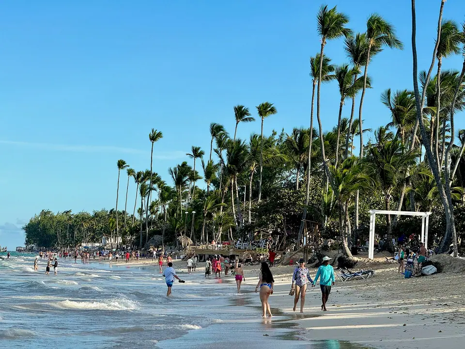 Palm-lined Bávaro Beach in Punta Cana with people walking along the shoreline in late-afternoon sun