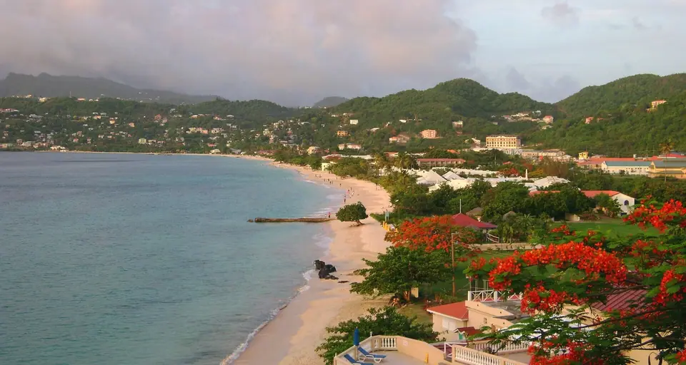 Long curve of Grand Anse Beach in Grenada with green hills behind