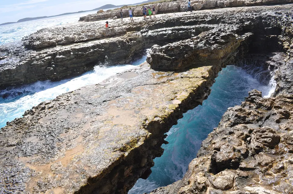 Natural limestone arch of Devil's Bridge with waves breaking on Antigua's east coast