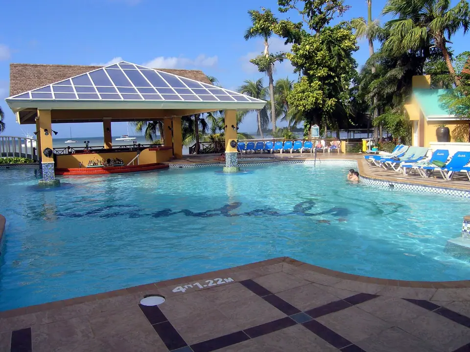 Large free-form main pool surrounded by palms and loungers at Sandals Negril