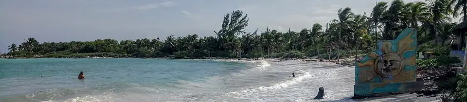 Wide panorama of the calm, clear water and white sand of Xpu-Ha beach with jungle along the shore