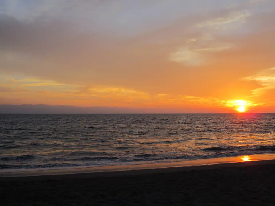Orange sunset over Banderas Bay in Puerto Vallarta with palm silhouettes