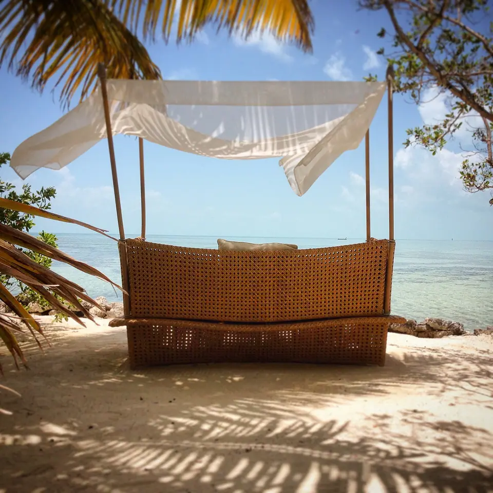 Shaded daybed on the beach at Cayo Espanto facing clear shallow water