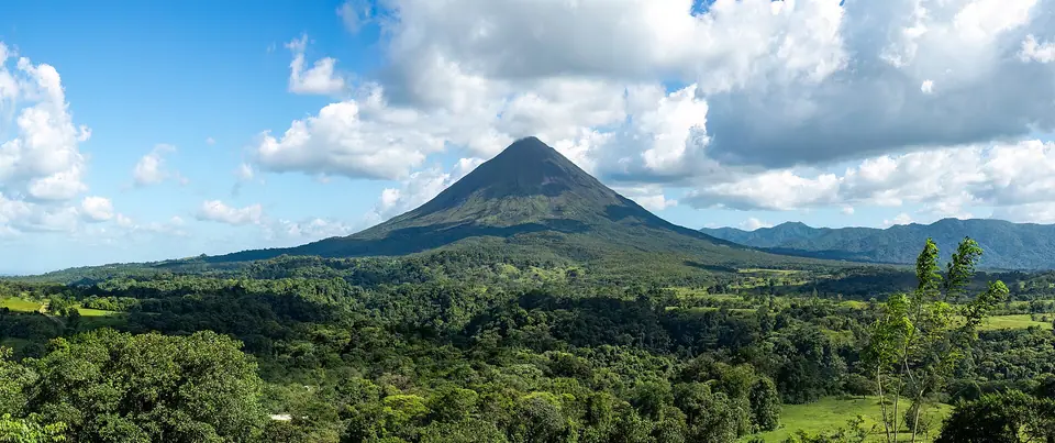 Panorama of the cone of Arenal Volcano above forest and farmland