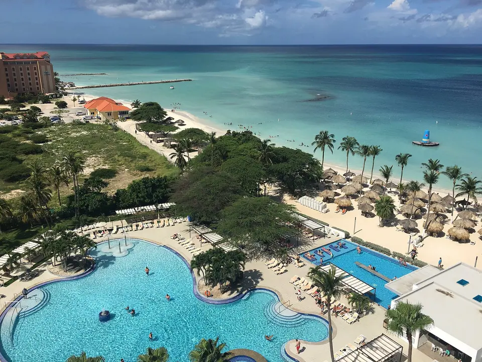 View from the 12th floor of Riu Palace Antillas over free-form pools, thatched palapas, Palm Beach and a pier