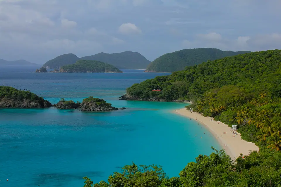 Trunk Bay on St. John with white sand, palm trees and a small cay offshore