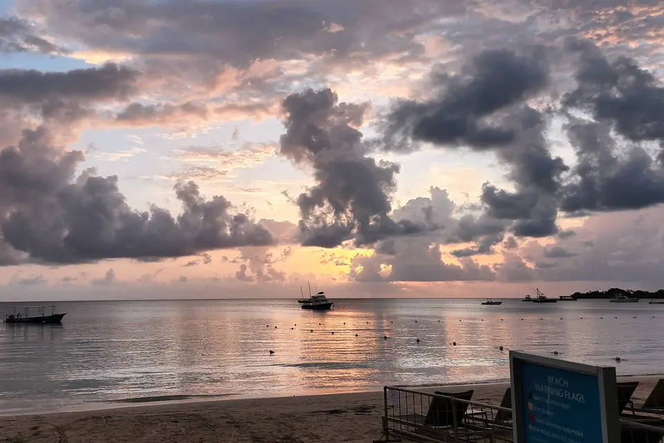 Orange sunset over the sea and silhouetted palm trees in Negril, Jamaica