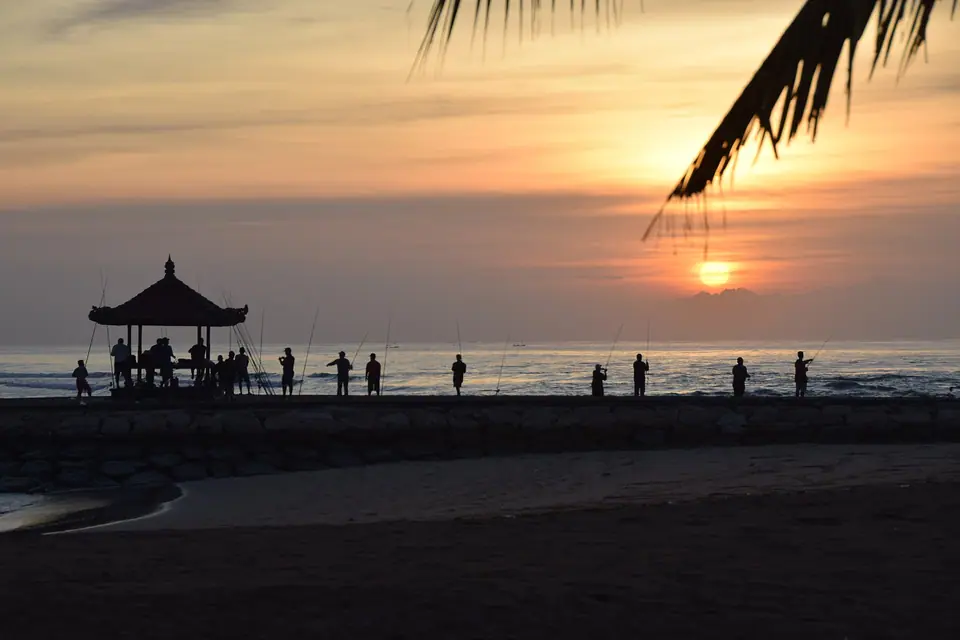 Fishermen on the sand at sunrise on Nusa Dua beach in Bali