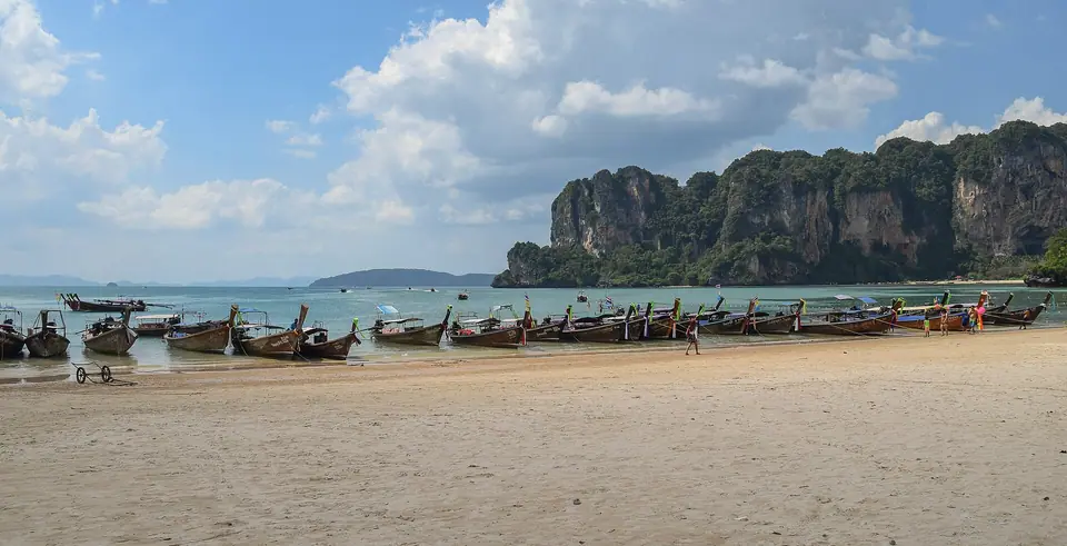 West Railay beach in Krabi, Thailand, with limestone cliffs and longtail boats on calm water