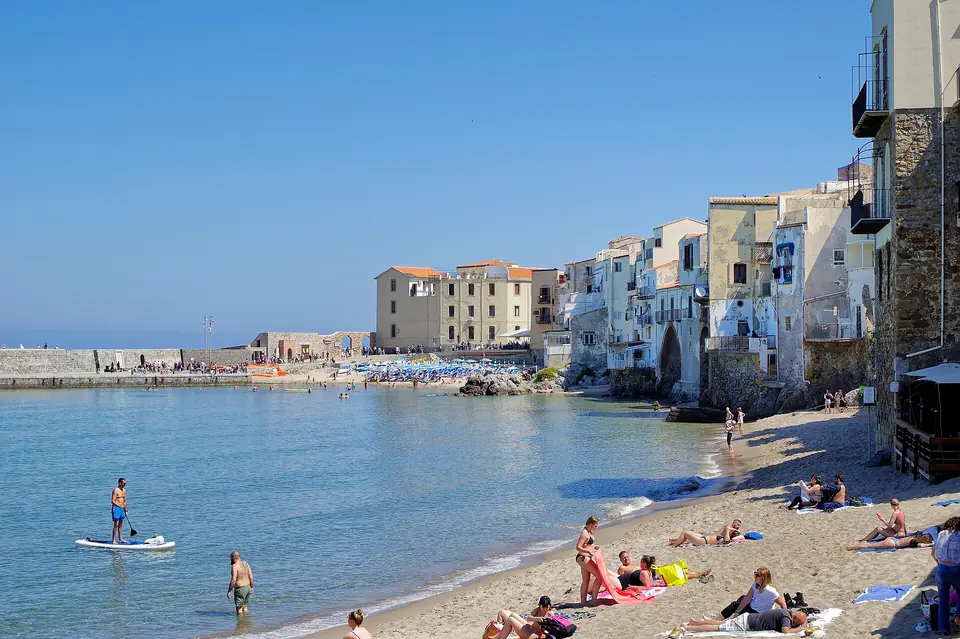 Cefalù beach in Sicily with the old harbor and the town's rock headland behind