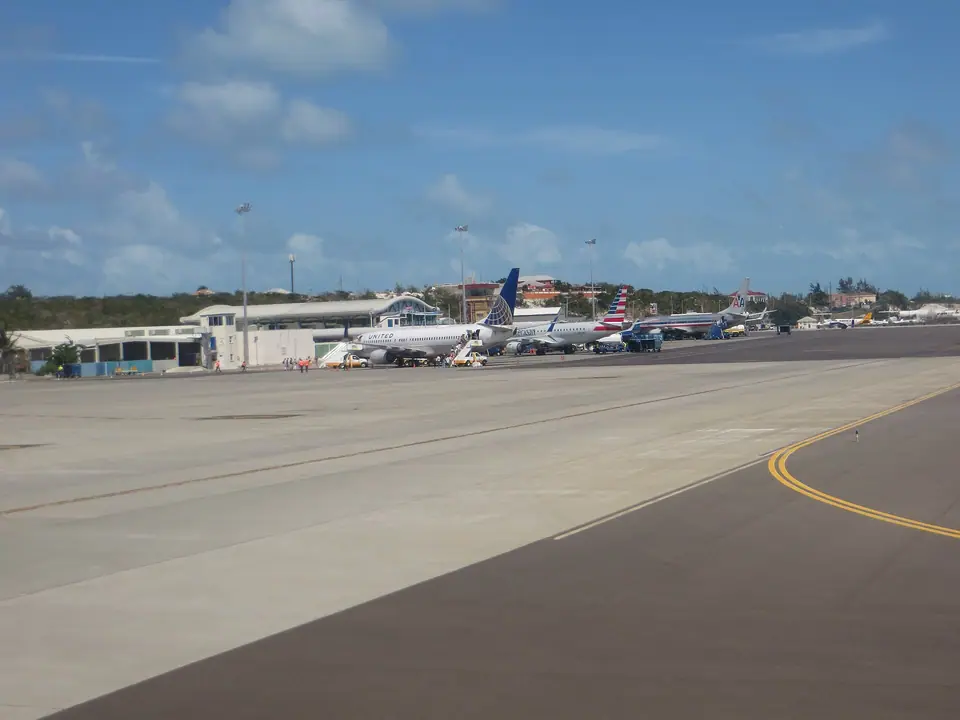 American and United Airlines jets parked at the terminal of Providenciales International Airport under a blue sky