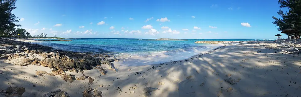 Sandy beach with low rocks and shade trees on the far side of the Sandals offshore island off Cable Beach