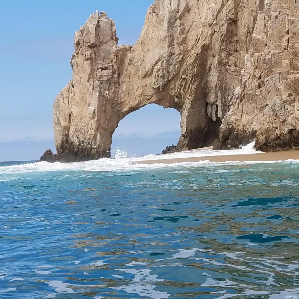 The eroded rock arch at Land's End in Cabo San Lucas with waves breaking on a small beach