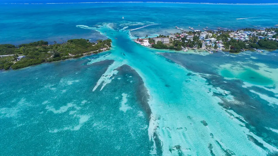 Aerial view of Caye Caulker with shallow turquoise water and the reef line beyond