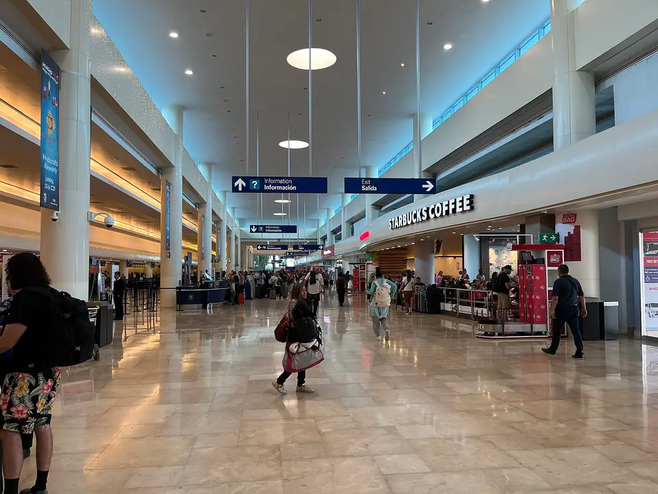 Terminal 3 building at Cancun International Airport with parked cars in front