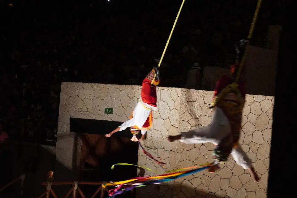 Voladores performers swinging on ropes from a tall pole at Xcaret park