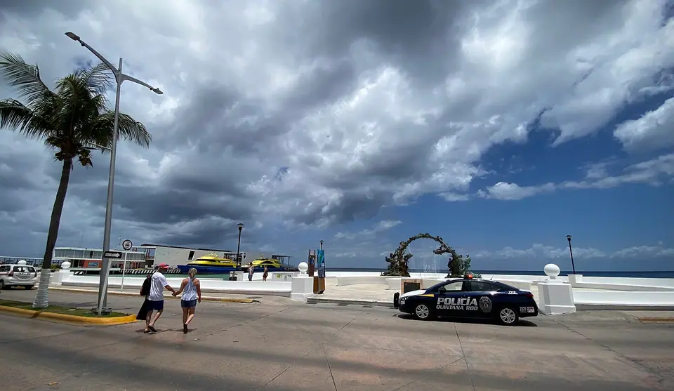 Waterfront plaza at the Playa del Carmen ferry dock in San Miguel de Cozumel, with palm trees, streetlights and storm clouds overhead