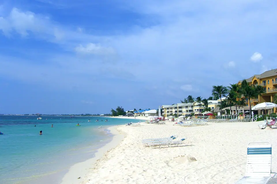 Low-rise resorts and palm trees lining the sand on Seven Mile Beach, Grand Cayman