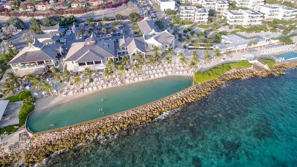 Aerial view of the Jan Thiel hotel zone on Curaçao with low-rise resort buildings, a lagoon-style swimming area and turquoise sea
