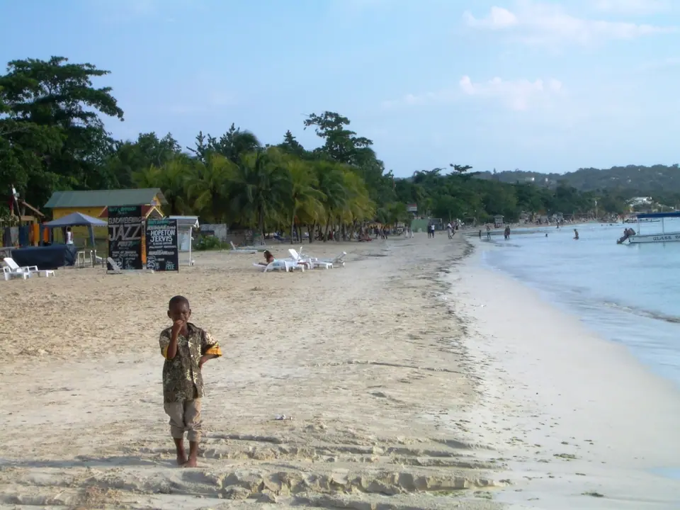 Long stretch of pale sand and shallow water on Seven Mile Beach in Negril
