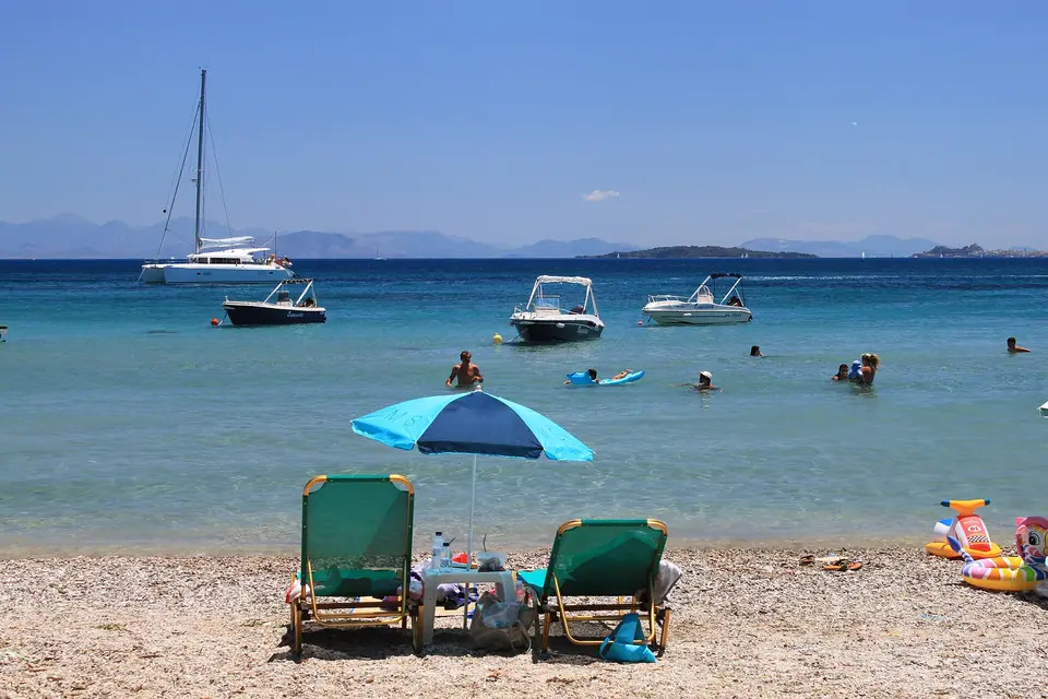 Pebbly beach with sunbeds and calm blue water at Dassia on Corfu, Greece
